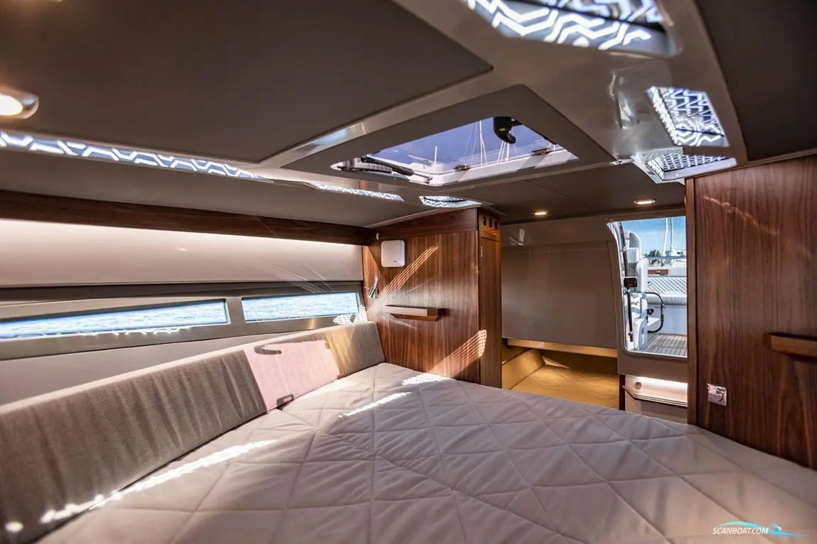 A spacious yacht interior featuring a double bed, wooden cabinetry, and a skylight, with a view of the water outside.